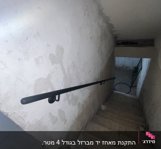 מעקה מתכת שחור לאורך גרם מדרגות בטון